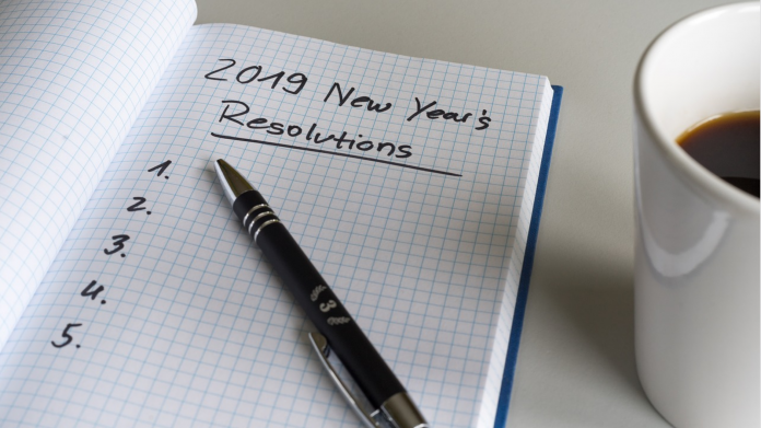 pen on paper about to write new year's resolutions with coffee