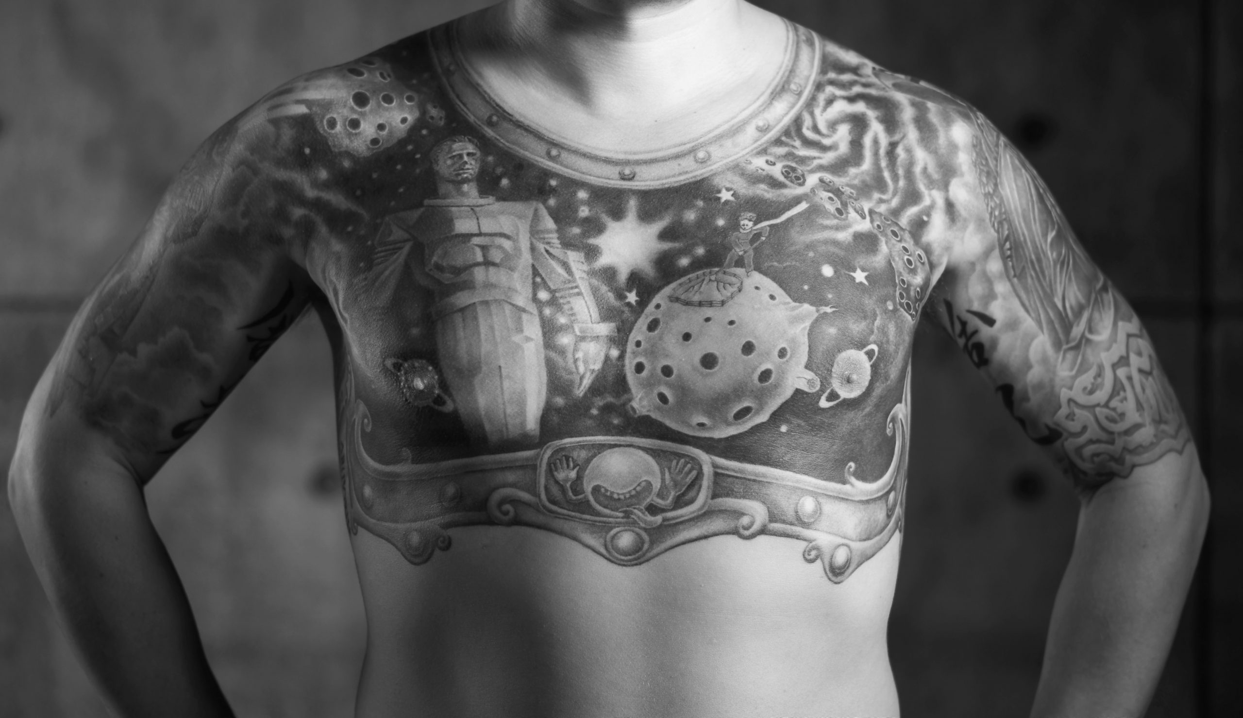 A black and white image of a man's chest featuring a large tattoo