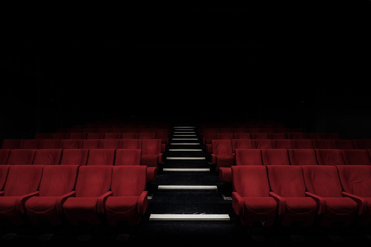 Rows of red cinema seats extend upwards, either side of a series of steps