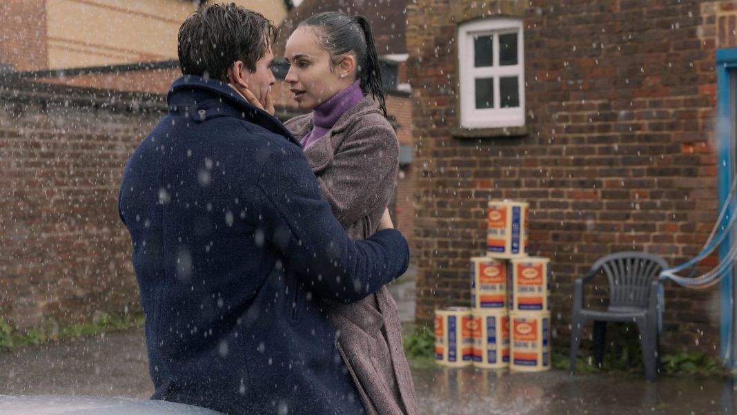 Two actors in the Netflix movie 'My Oxford Year' performing a scene in the rain.