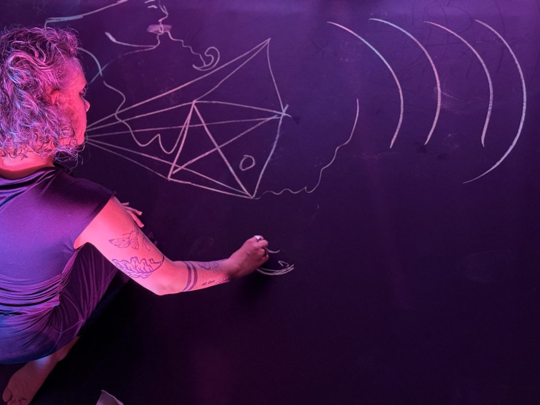 A woman draws with chalk as part of the performance of Timestamp.
