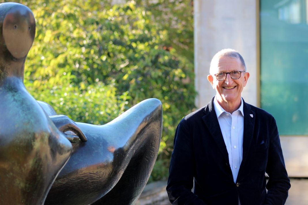 David Isaac, Provost of Worcester College and new Labour peer, smiles for camera next to bronze sculpture.